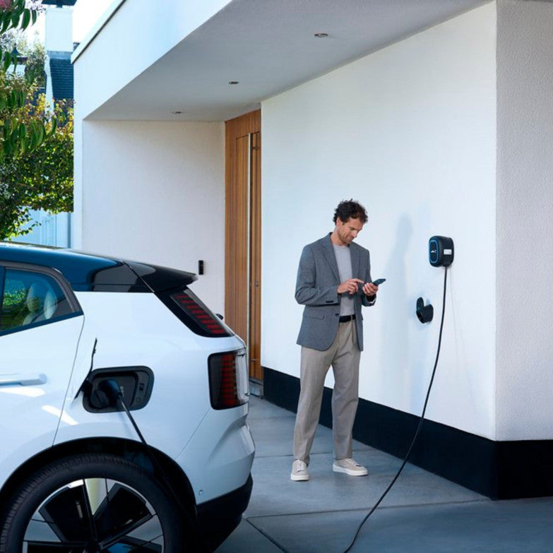Zar auto elettrica bianca collegata a una wallbox accanto a un'abitazione.